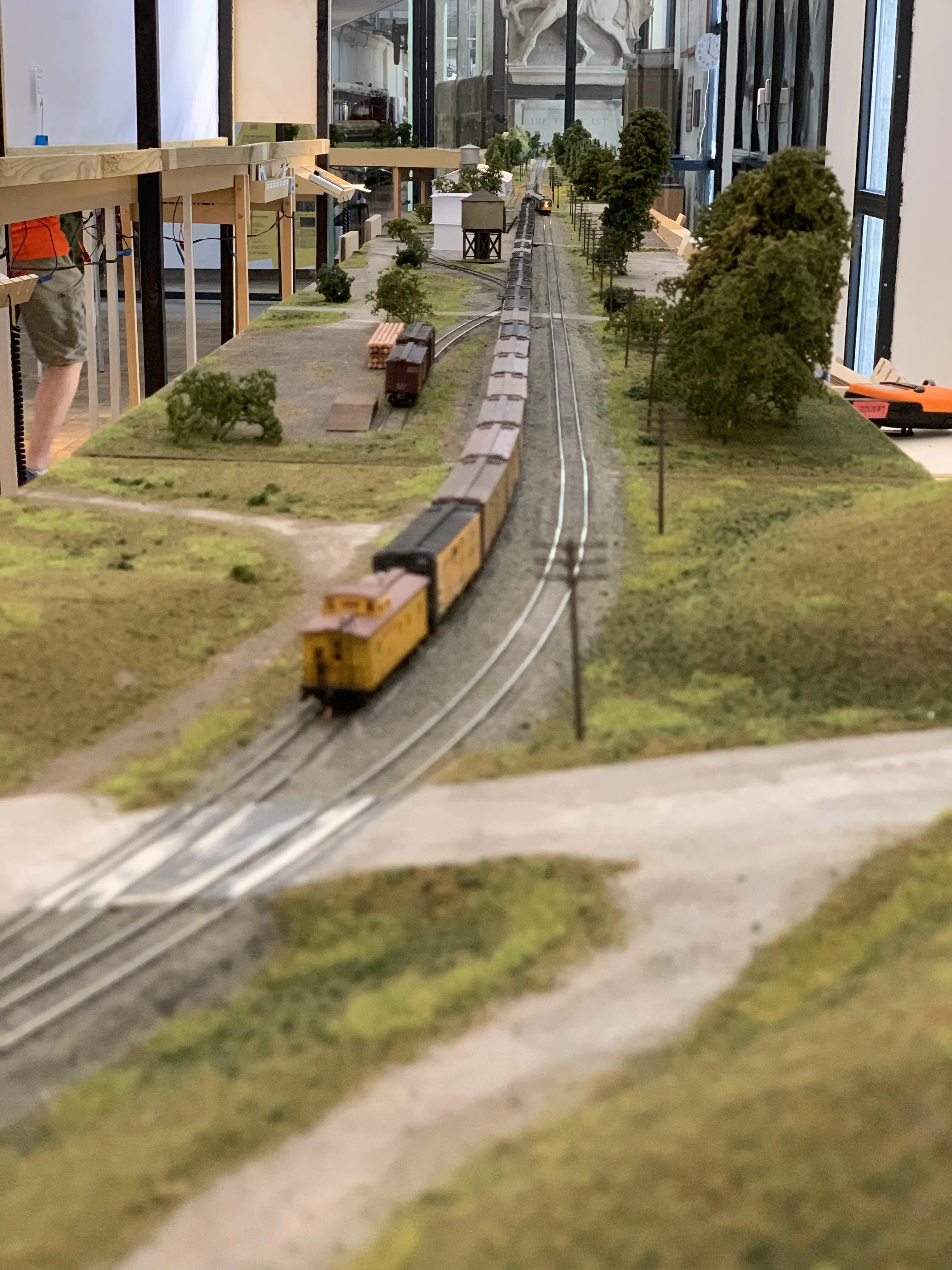 Looking over cascade and other modules in the far. Module totalling more than 10 m straight track. The team track to the left, with a few cars spotted. A 30 car refer extra is waiting on the siding to let a passenger train pass.